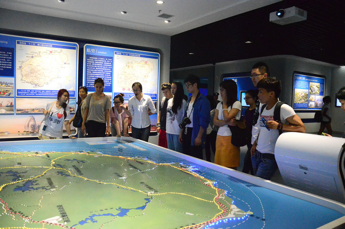 1432545895365187.jpg 留学生听取规划展览馆讲解员介绍海南交通布局.JPG